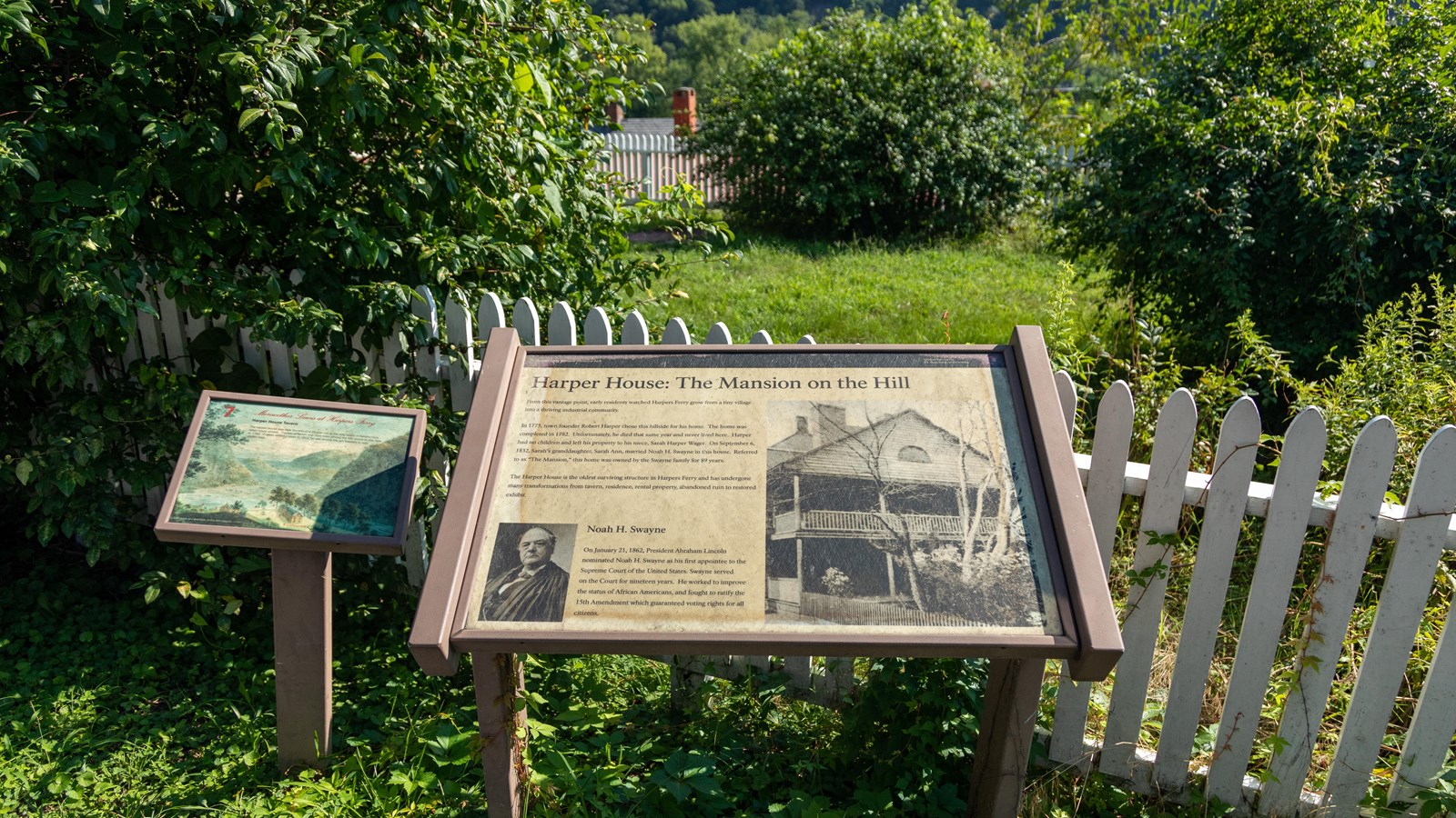 Two informational panels next to each other in front of a white fence. 