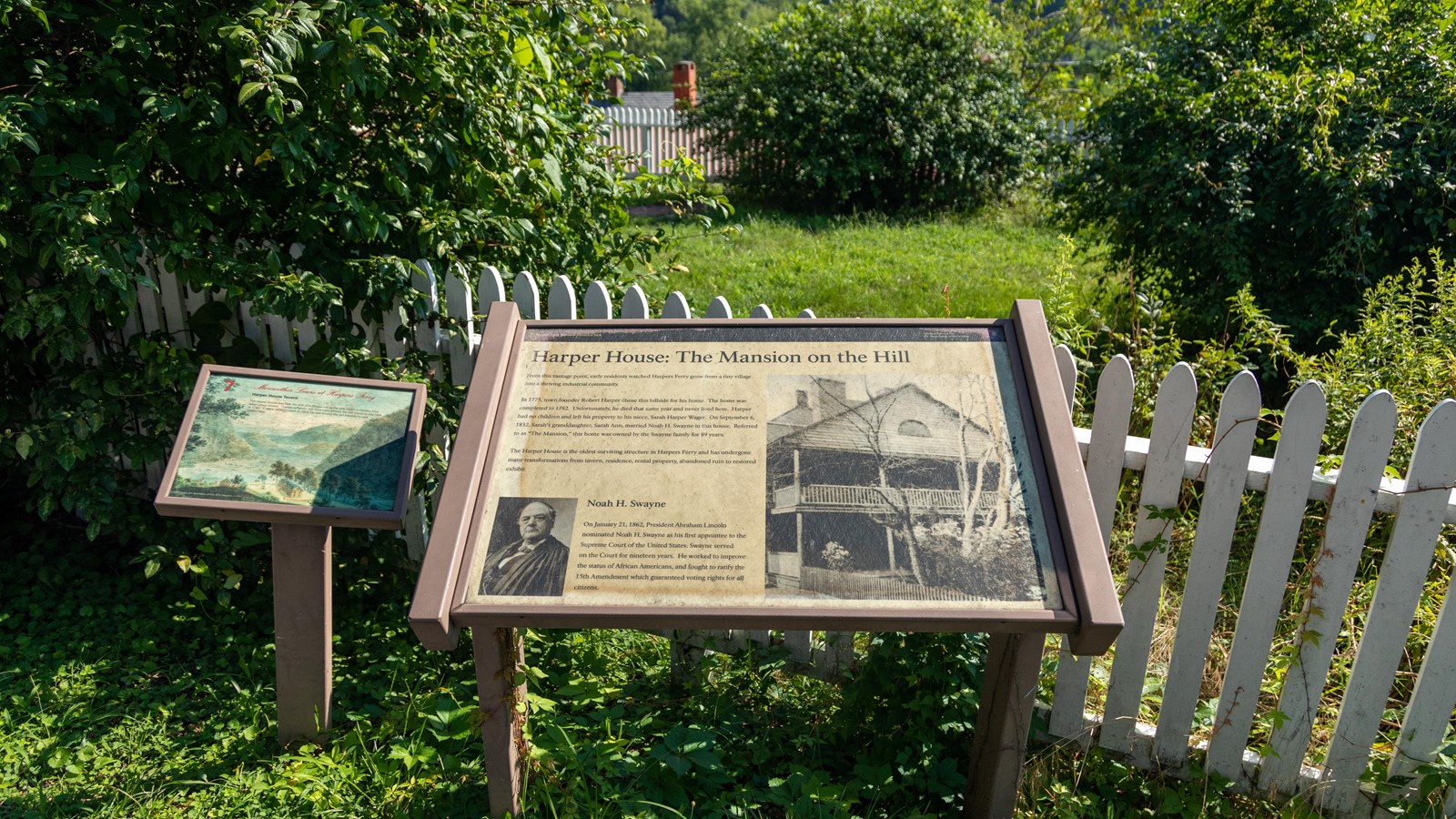 Two informational panels next to each other in front of a white fence.