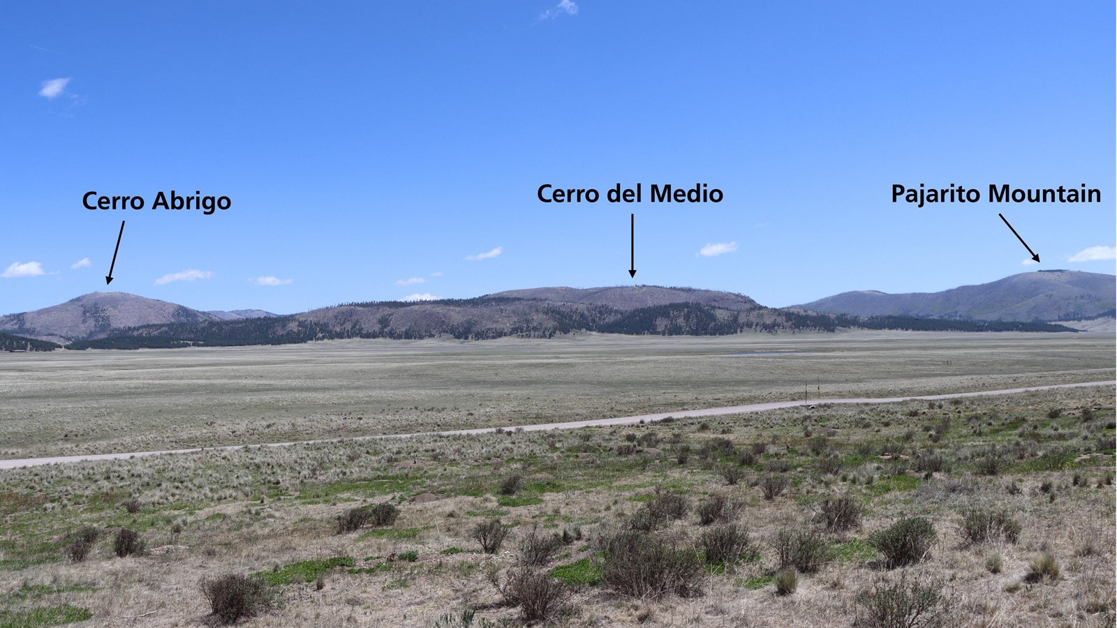 A vast, montane grassland with distant peaks and lava domes labeled.