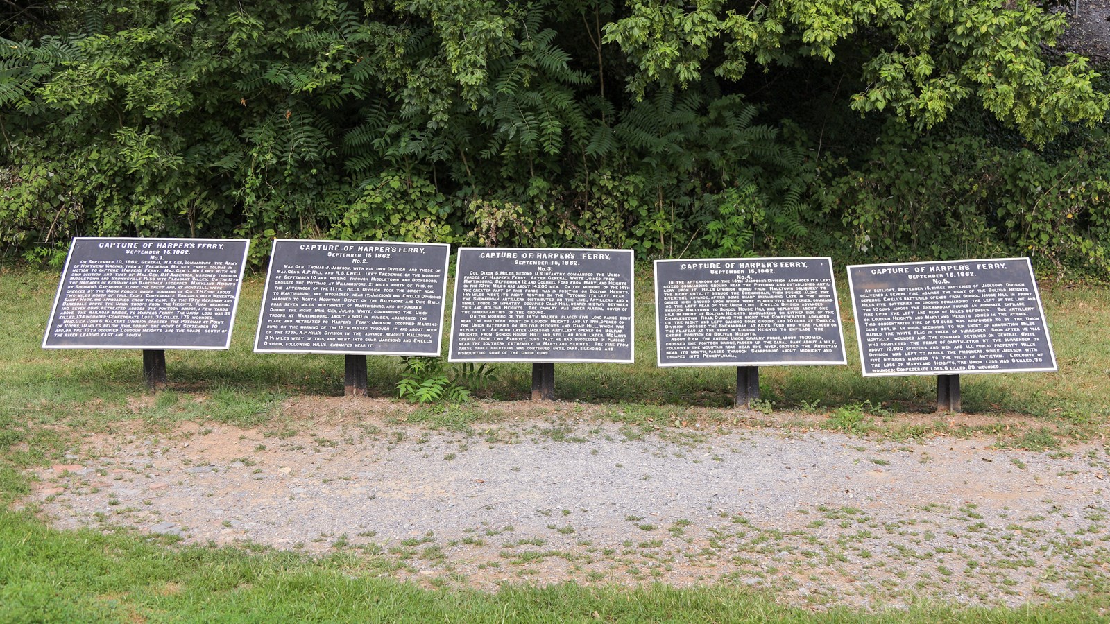 A row of five historical marker plaques low to the ground.