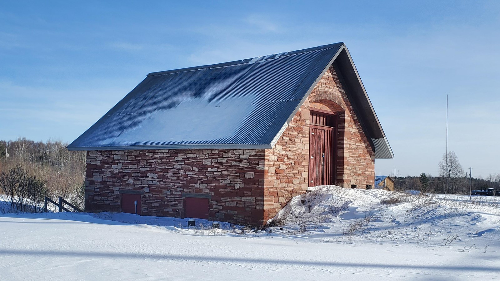 Winter scene of red and white Jacobsville sandstone building with steep corrugated metal roof.