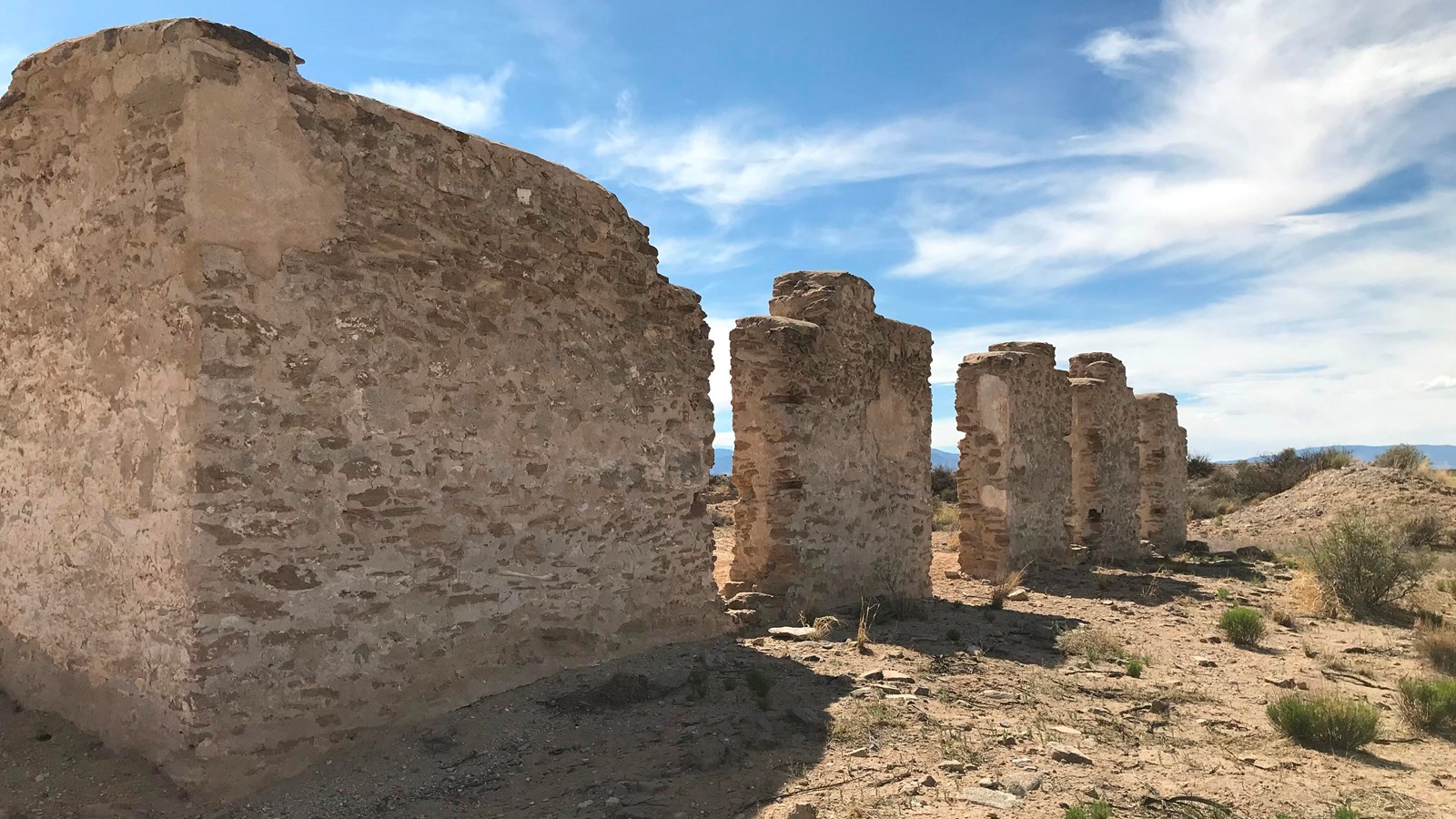 Adobe ruins of fort walls stand in a desert landscape.