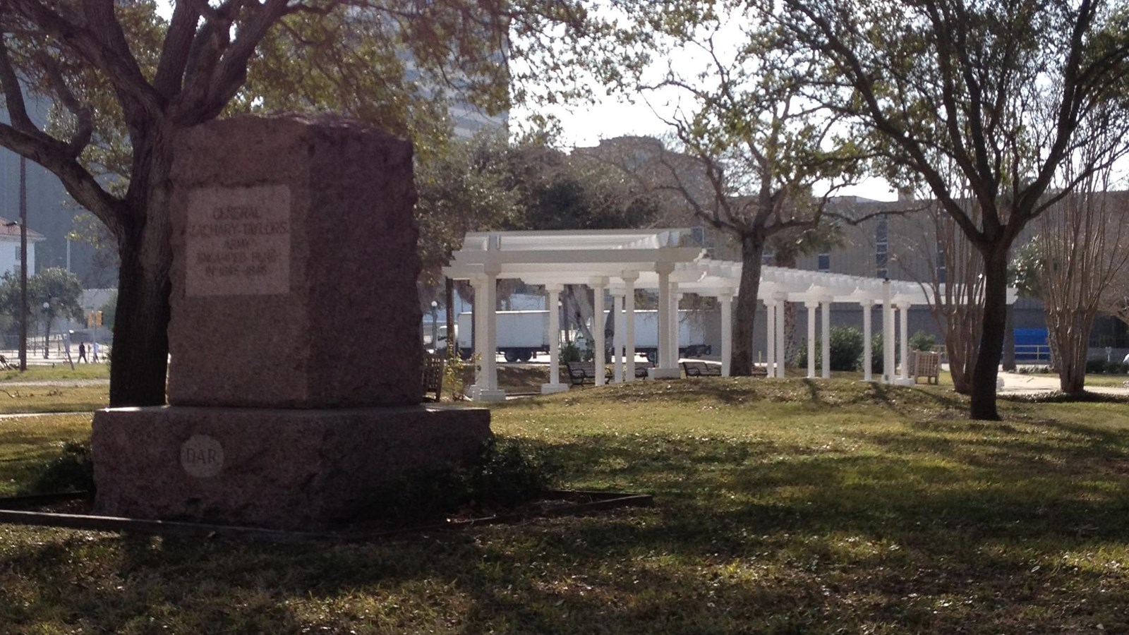 Artesian Park marker in foreground with white pergola in background