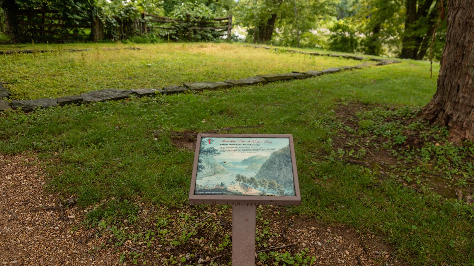 A information panel in front of an outline of ruins of an old house
