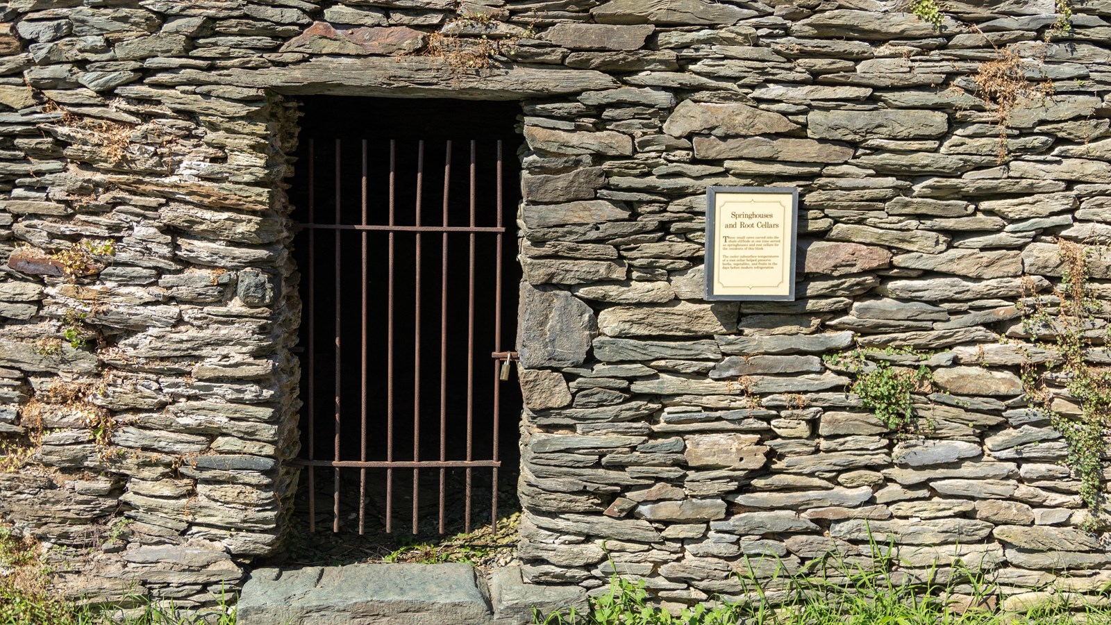 A windowless, stone building with an iron gate in the doorway.