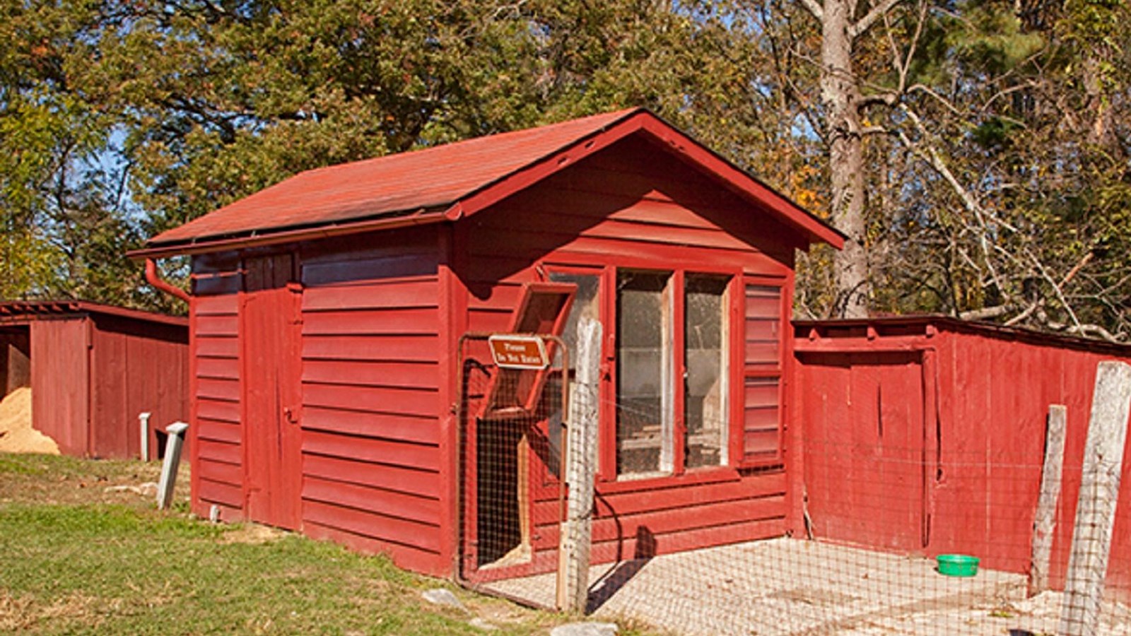 A little red building with windows and a hatch door for chickens