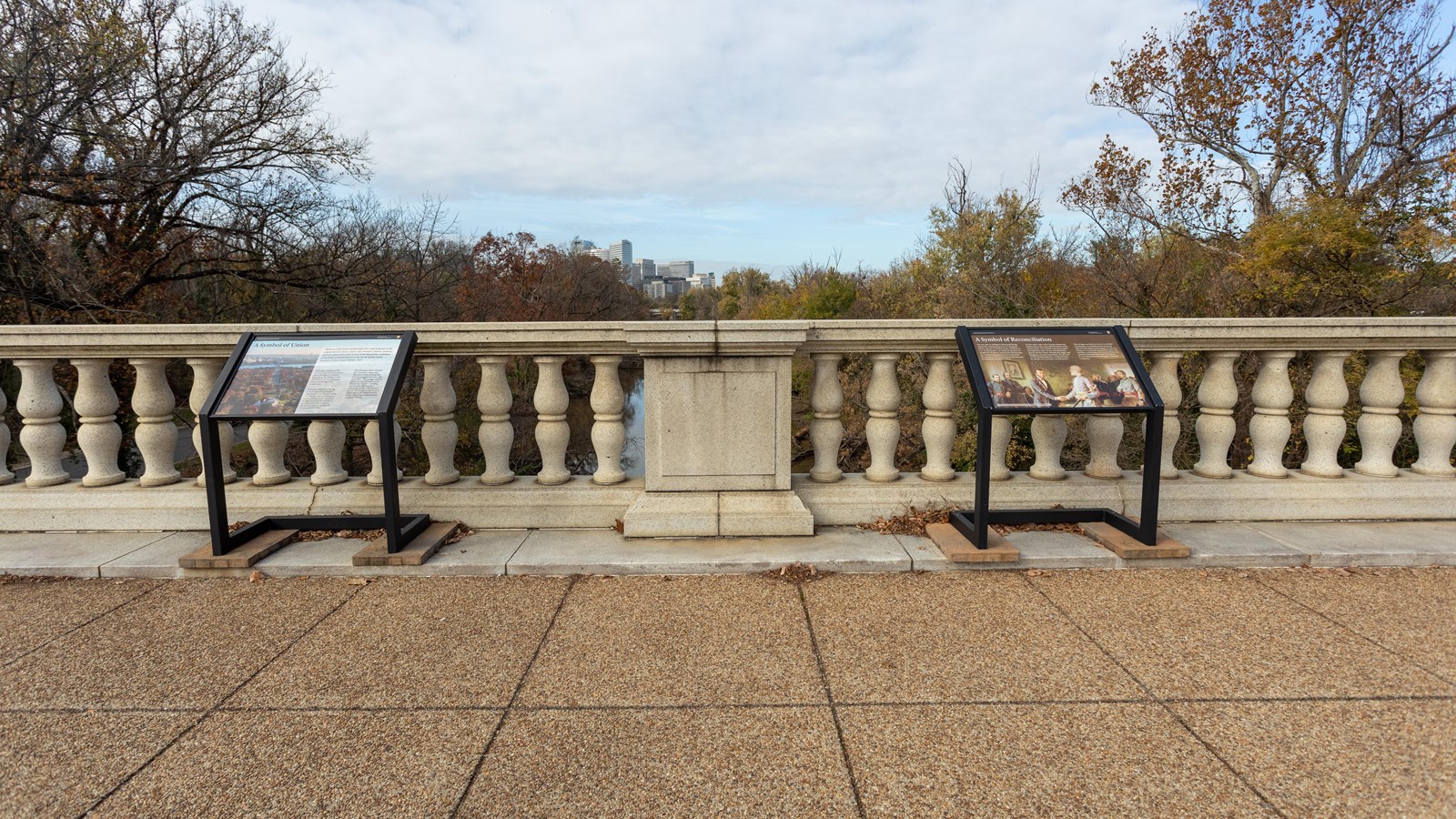 Twin information panels overlook a river from the bridge\'s stone railing.