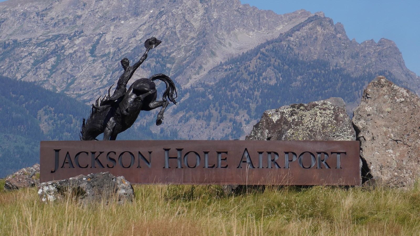 Jackson Hole airport sign with statue of cowboy in background