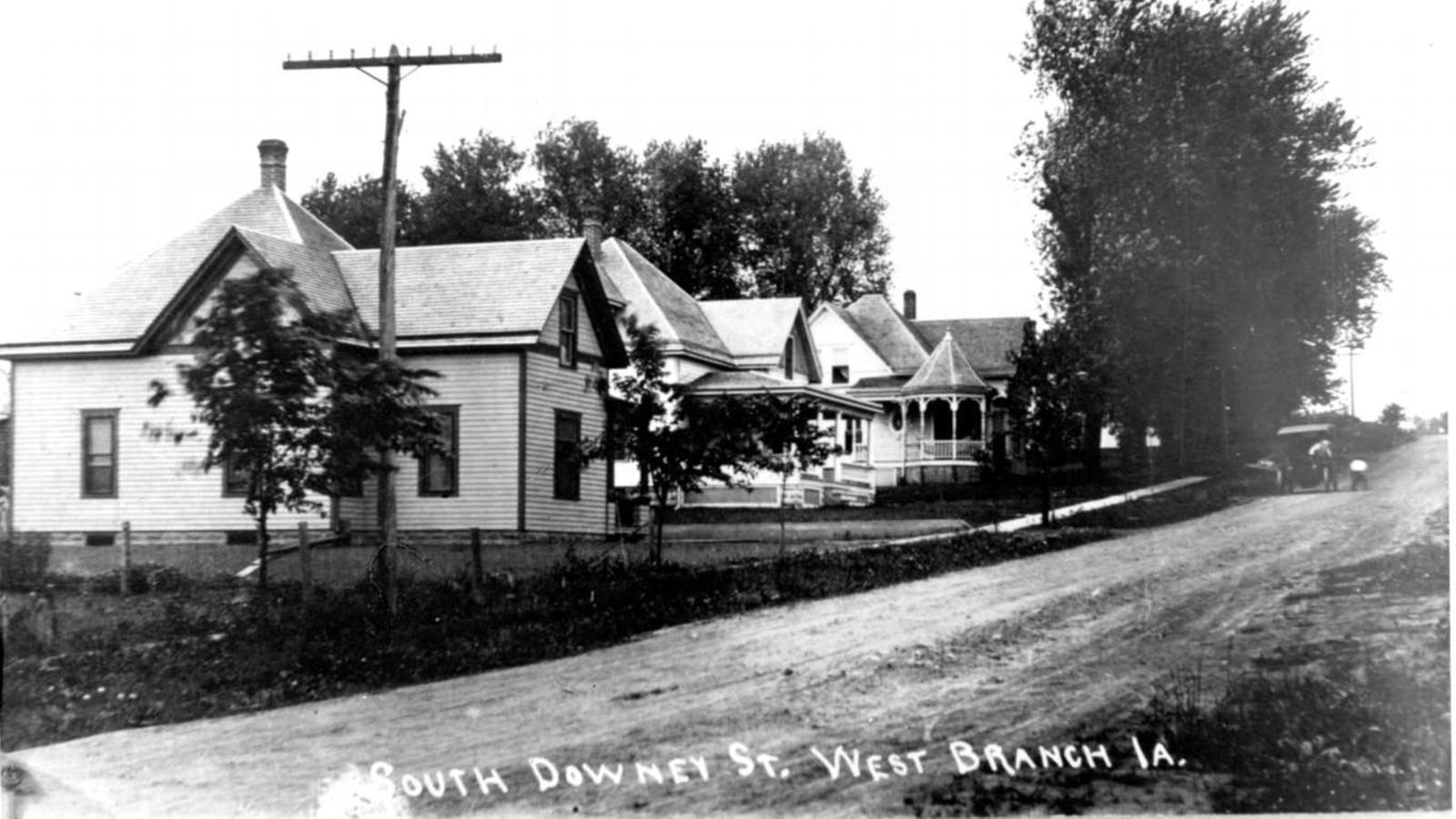 Houses and telephone lines line a small town street and in the background.