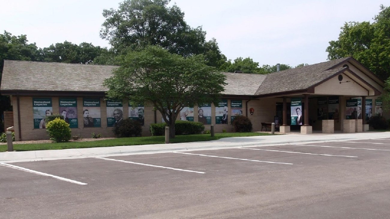 An l-shaped brick building with landscaped bushes and trees surrounding it.
