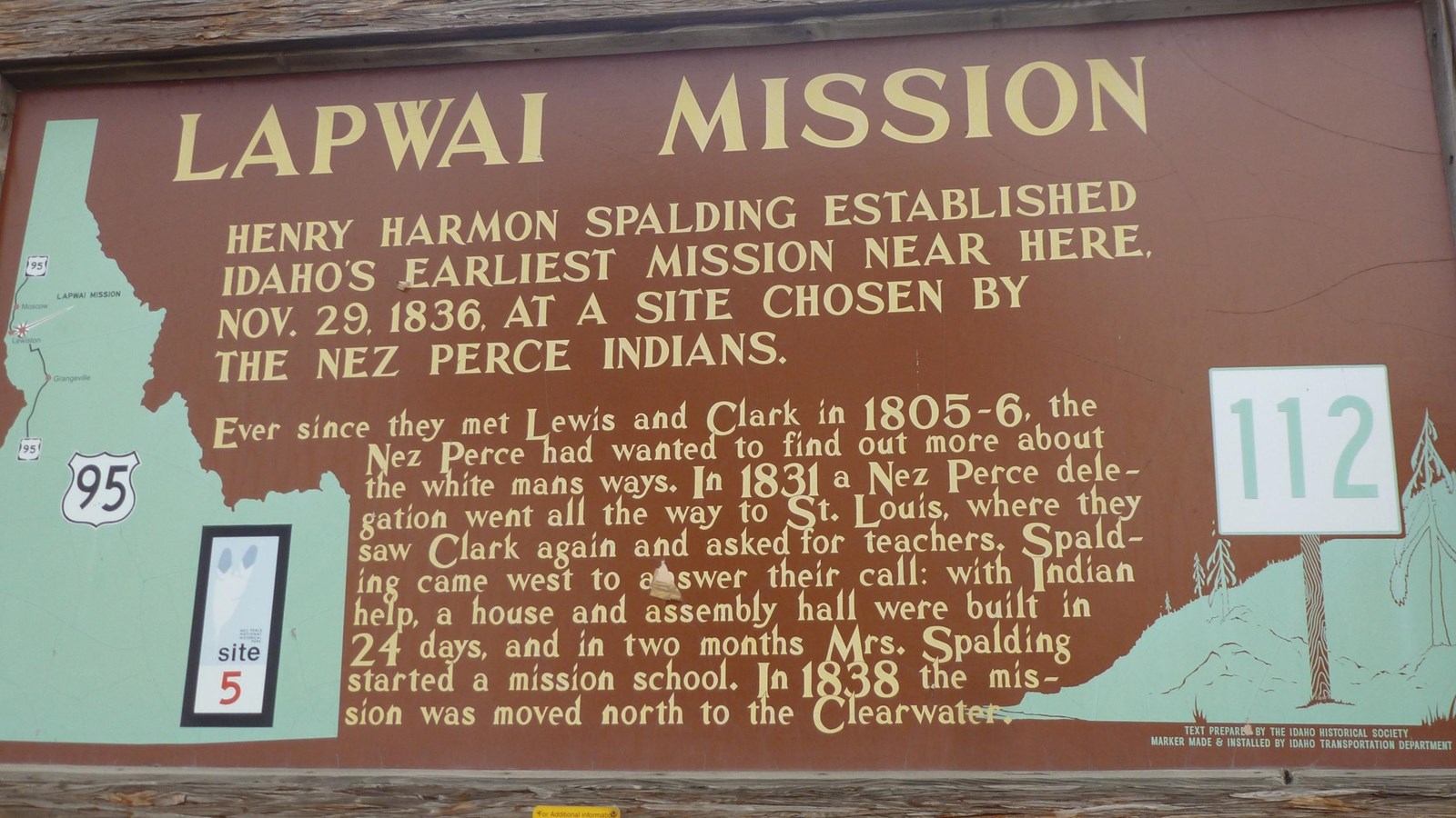 Wooden roadside sign with yellow text and brown background.
