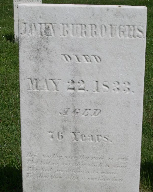 A white granite headstone with faded writing etched into it.