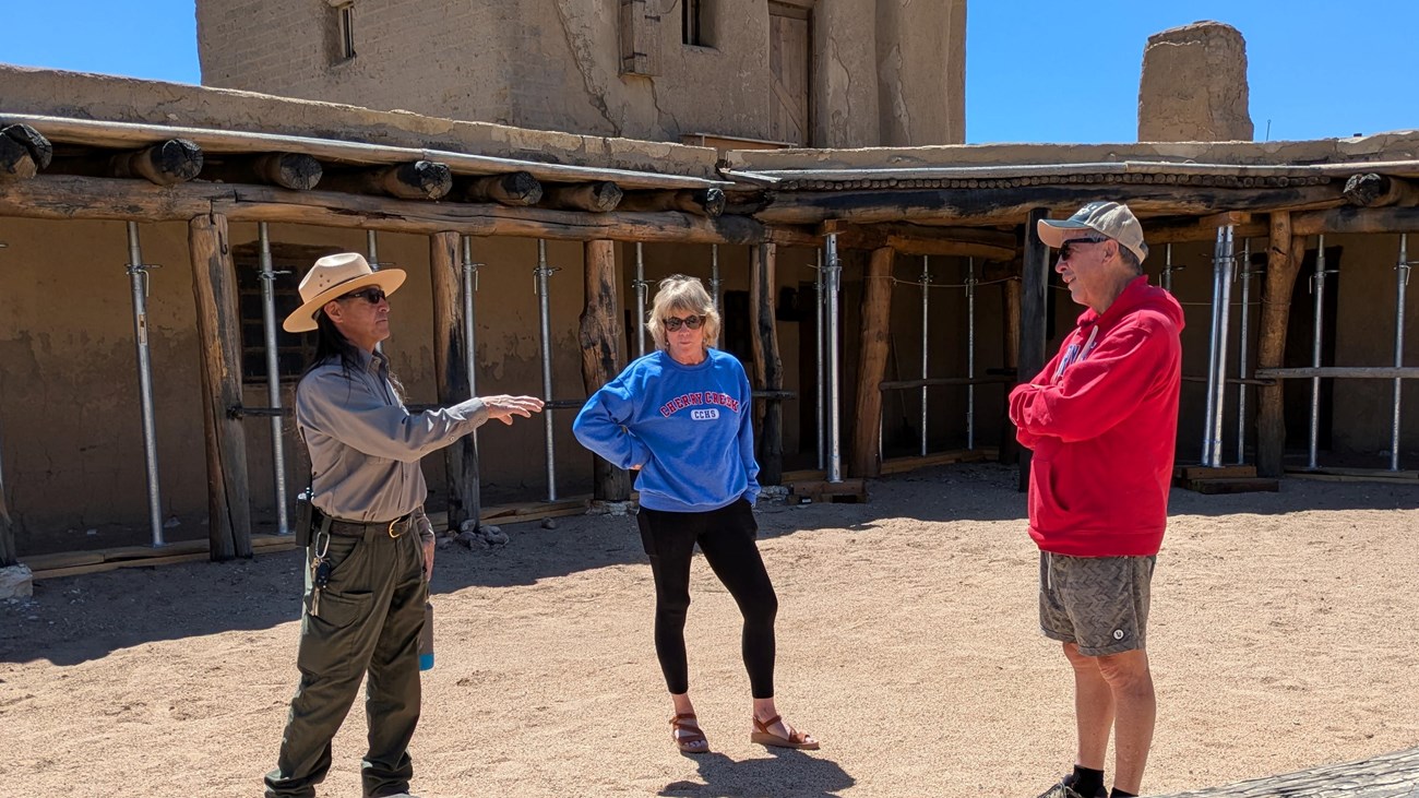 A park ranger talks to two visitors inside a plaza of the reconstructed fort.