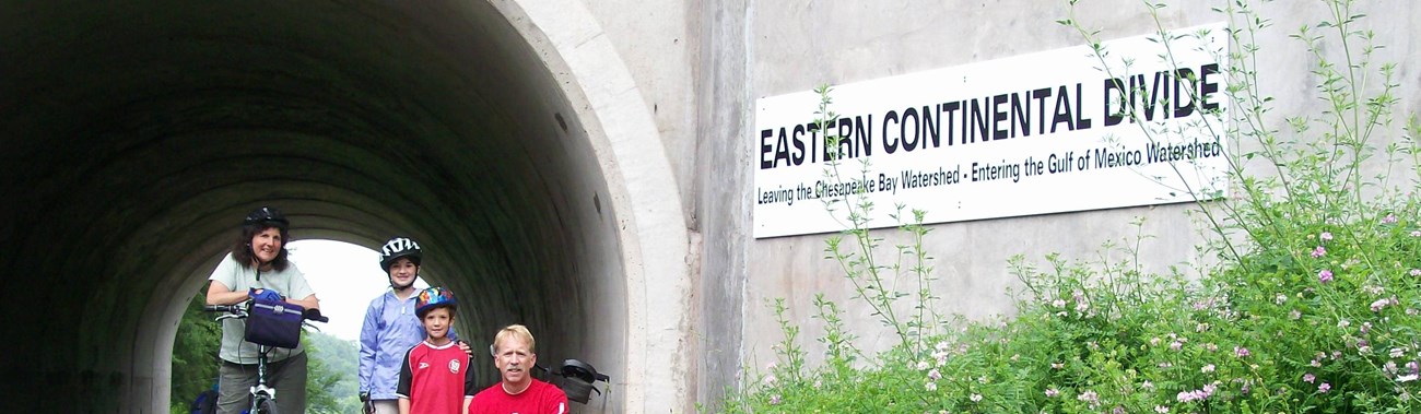 family of bicyclists at the Eastern Continental Divide on the Great Allegheny Passage rail-trail