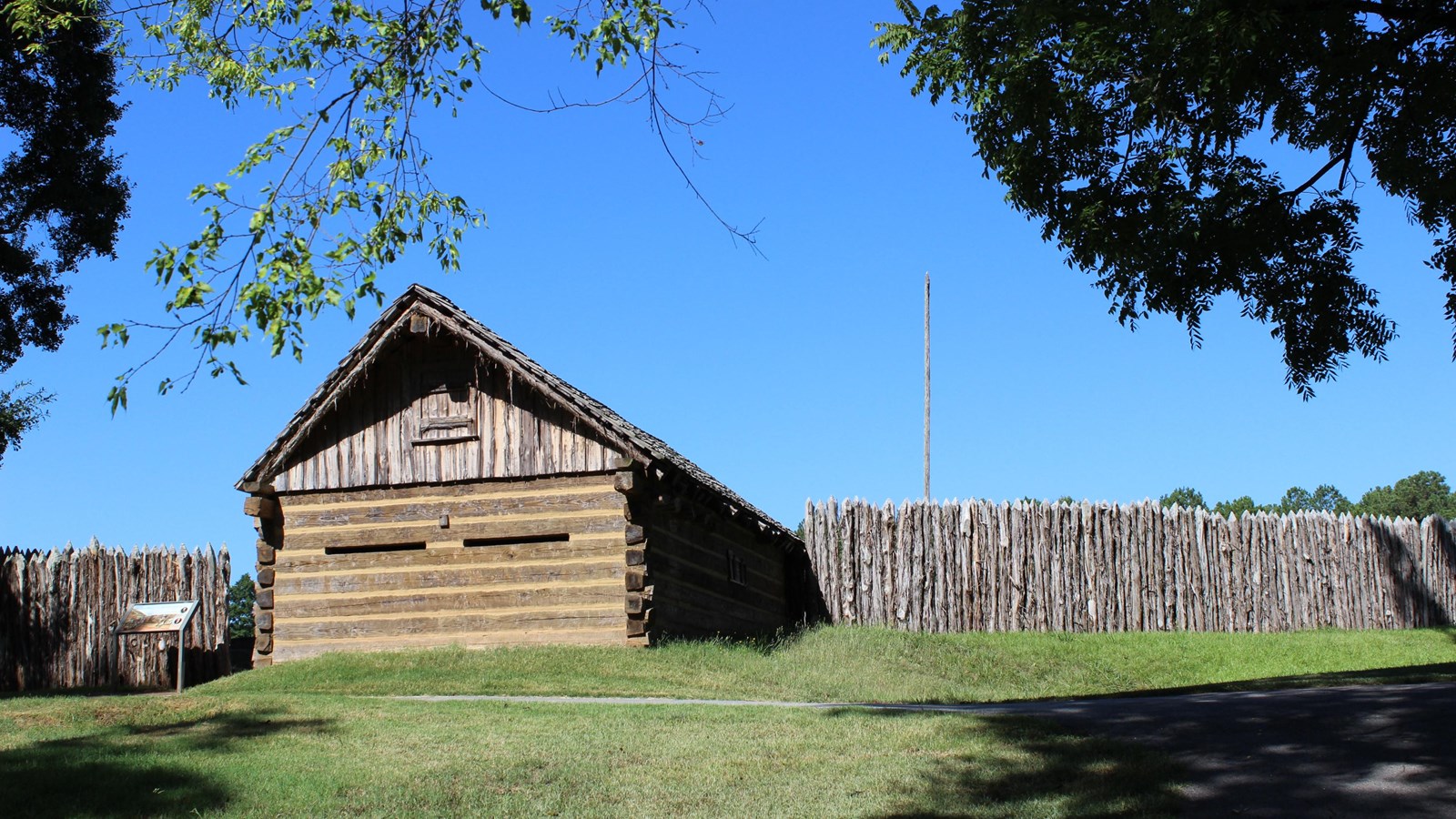 A wall made of vertical tightly placed wooden logs.