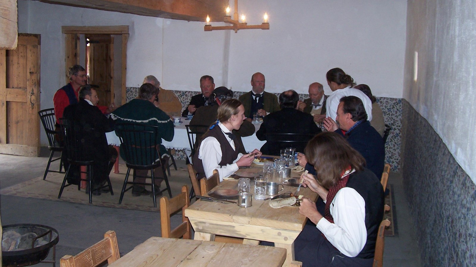 Men and women in historic costume at a long dining table