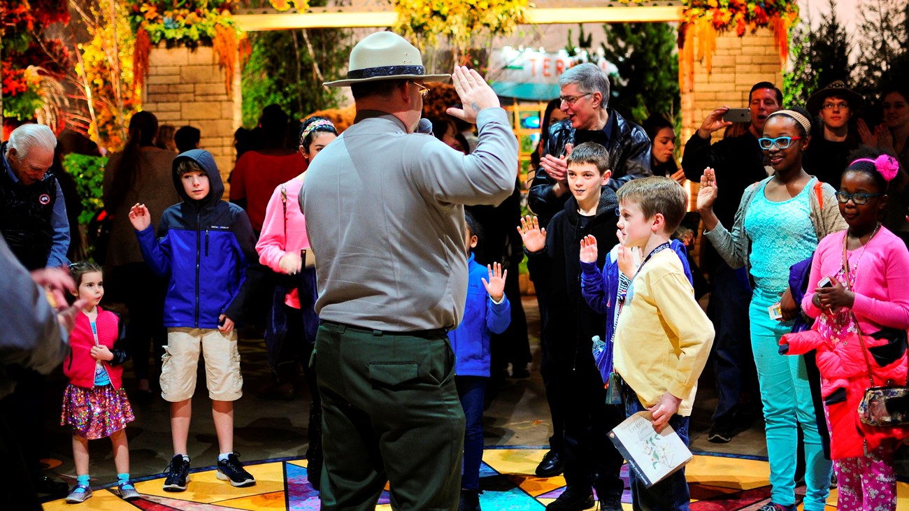 Children facing park ranger raise their right hands to take the oath of Junior Ranger.