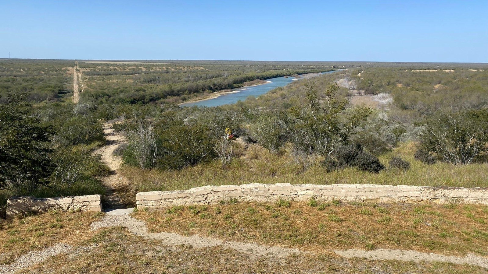 A dirt trail leading downhill to a body of water