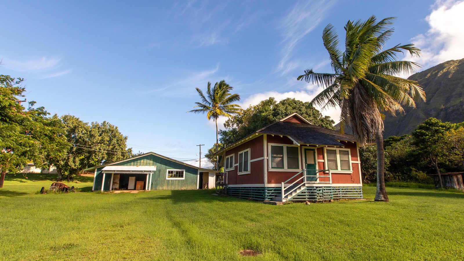 Two buildings, one blue and one red stand next to each other surrounded by a lawn. 