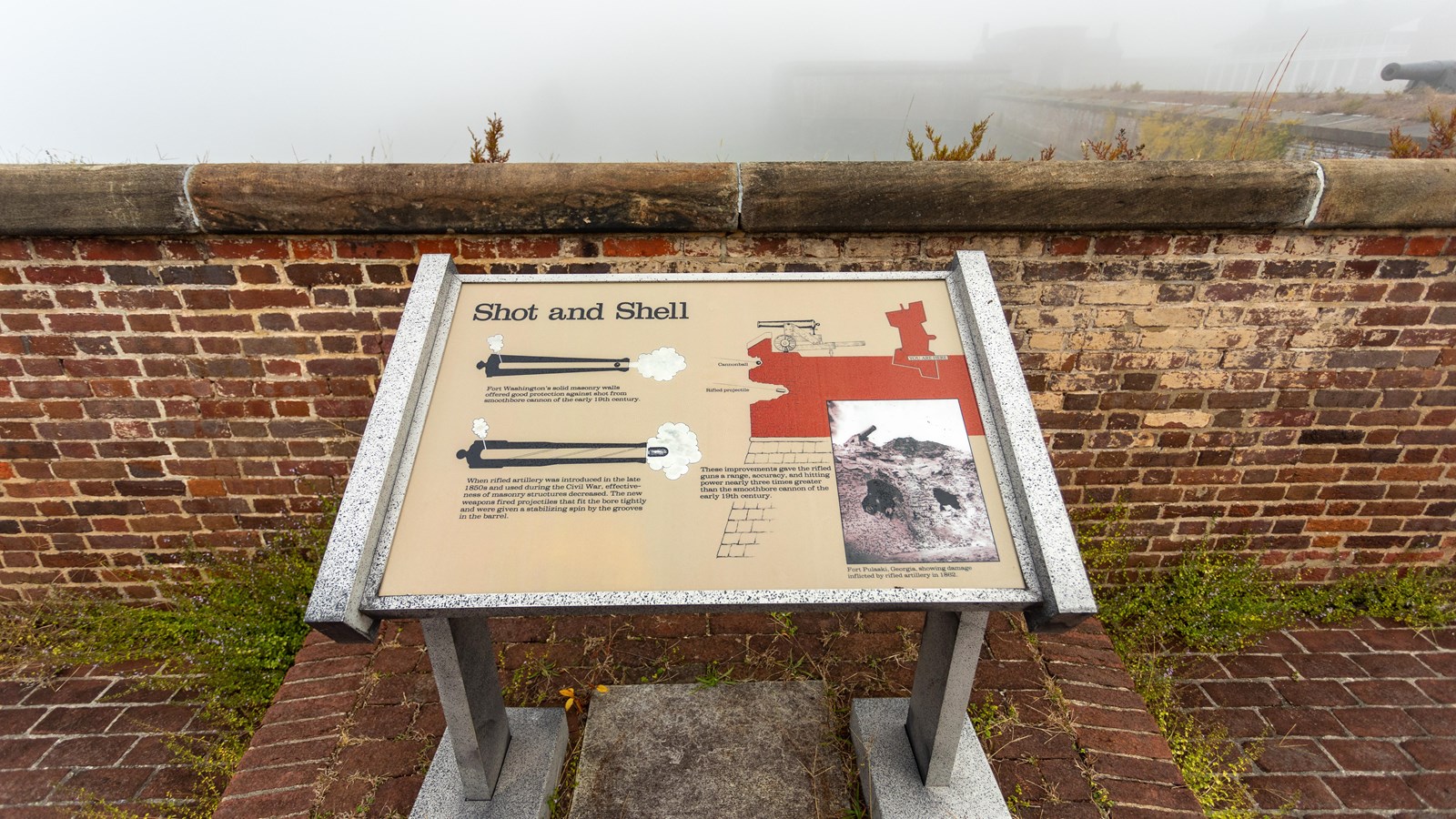 An interpretive-panel stands in front of a brick wall, featuring text, a photo, and three diagrams.