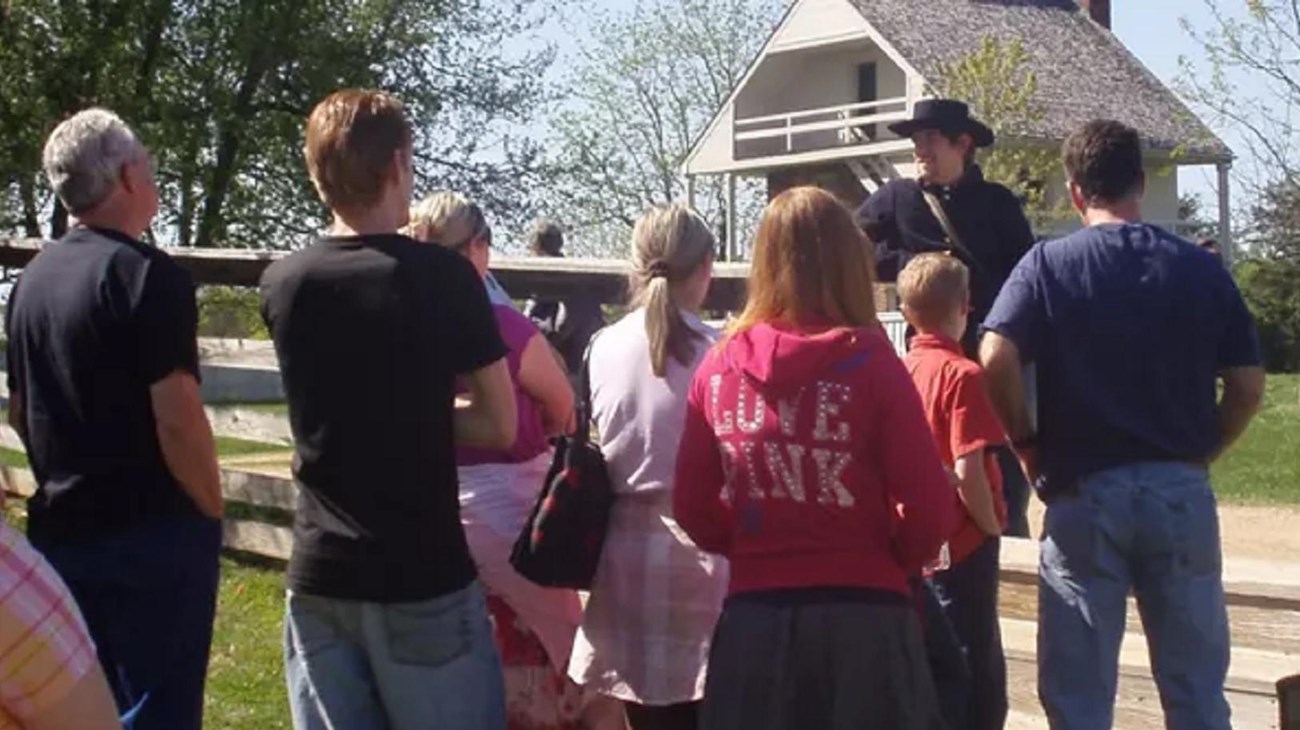 A man in a 1860s soldier uniform talks to visitors. 