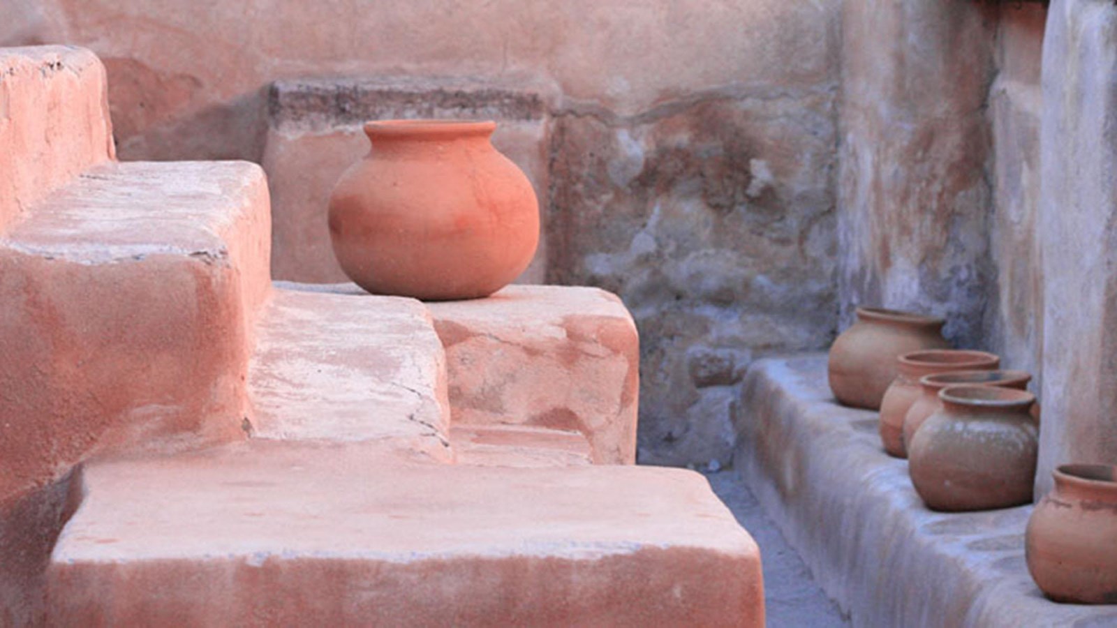 large steps in foreground with row of ceramic pots along a ledge in background