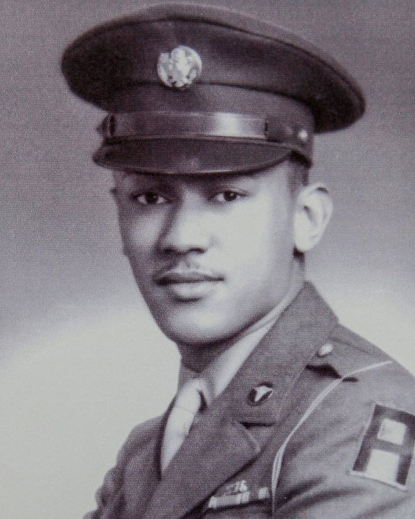 Black and white photo of African American man in US Army uniform with arms crossed looking at camera