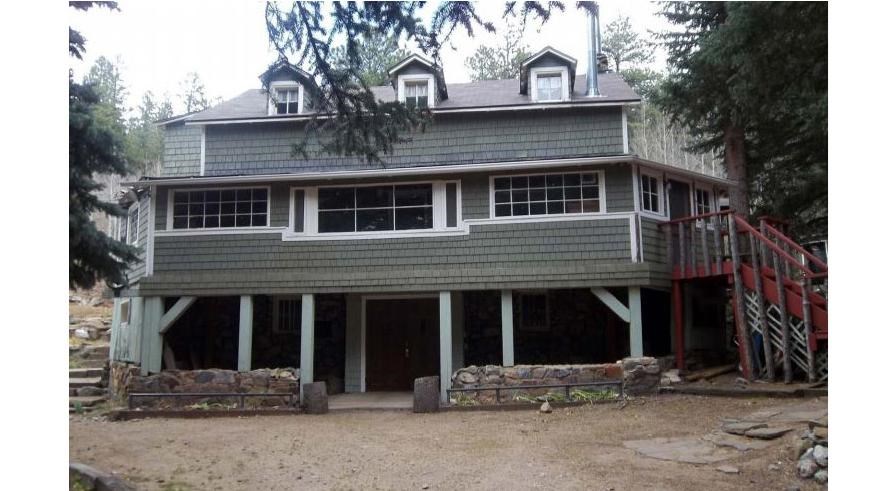 three story wood shingle house with a covered basement porch entrance 