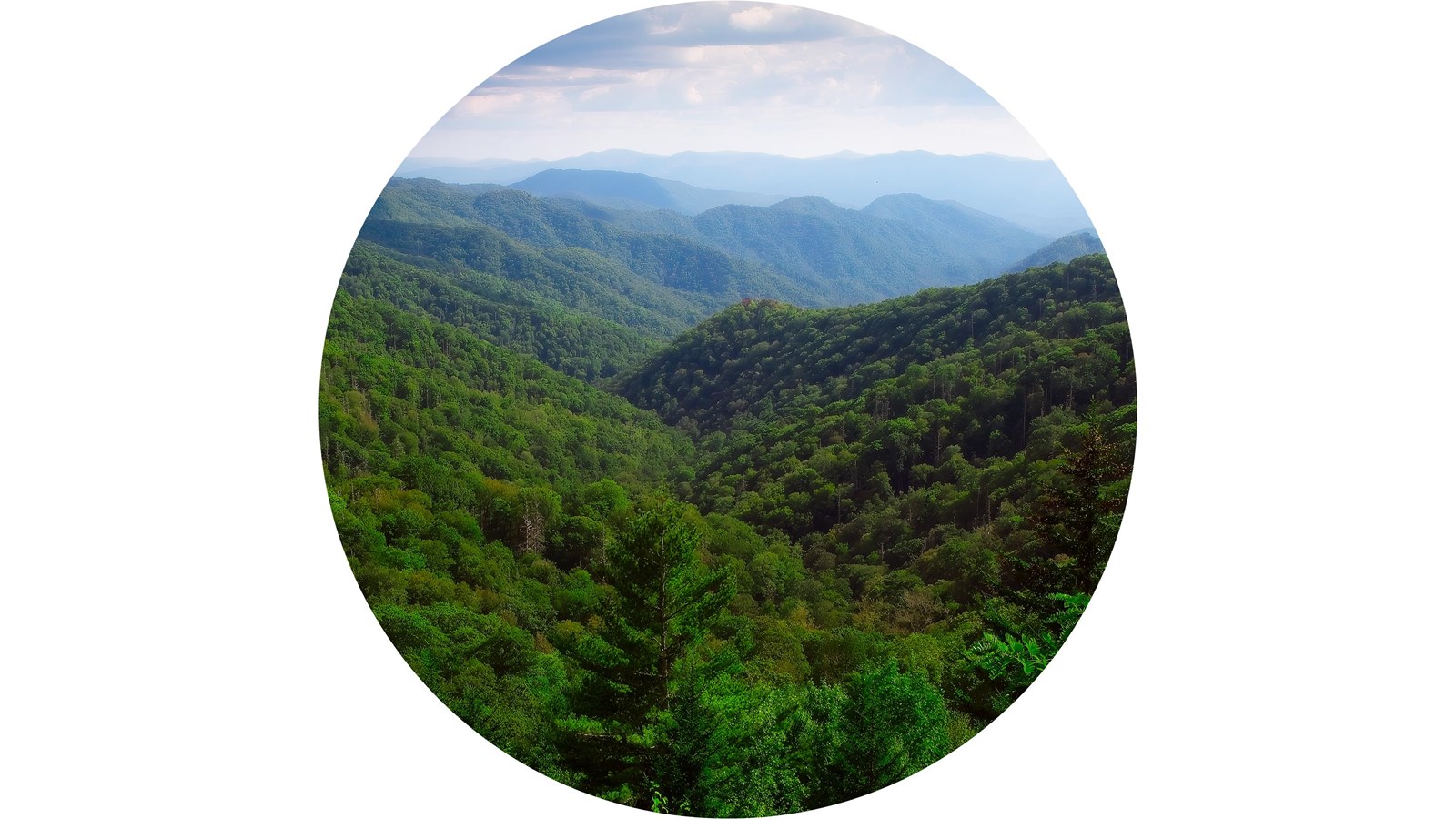 A valley between rolling mountains on a partly cloudy summer day.