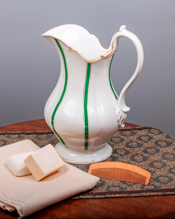 Grouping three items: a green and white wash pitcher, two pieces of lye soap, and a wooden comb.