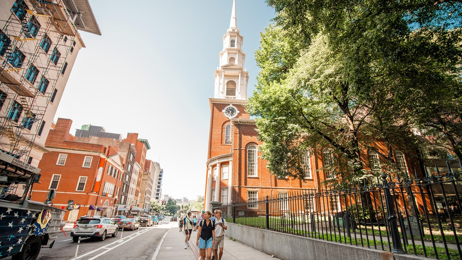 Park Street Church with its tall ornate steeple towering over the street against a blue sky.