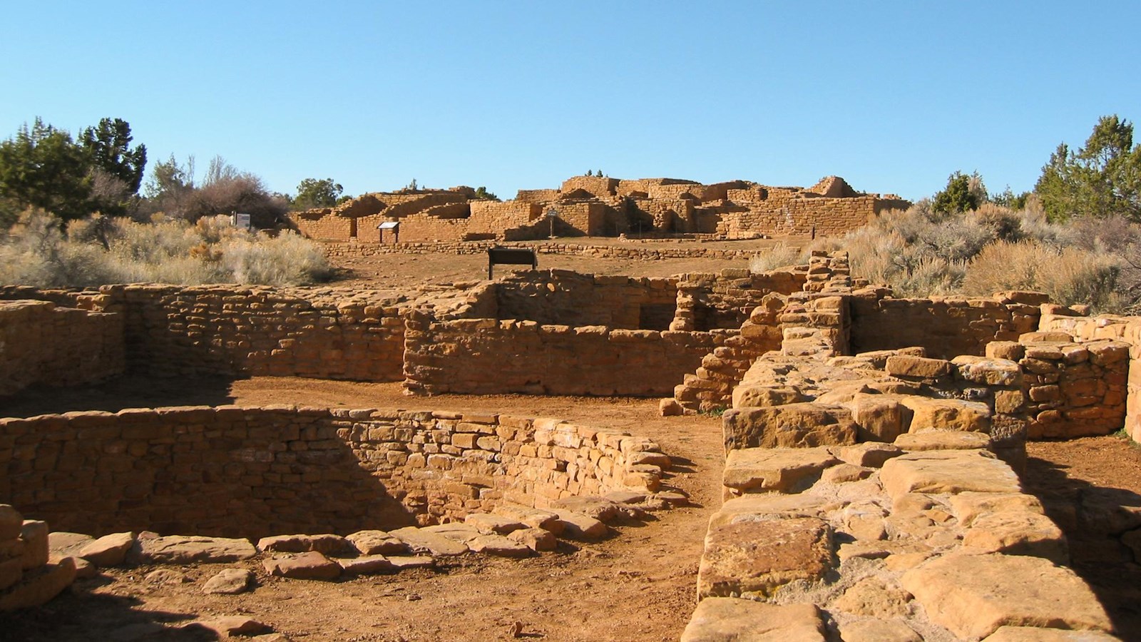 Looking across the tops of several low, ancient stone-masonry walls, both square and round.