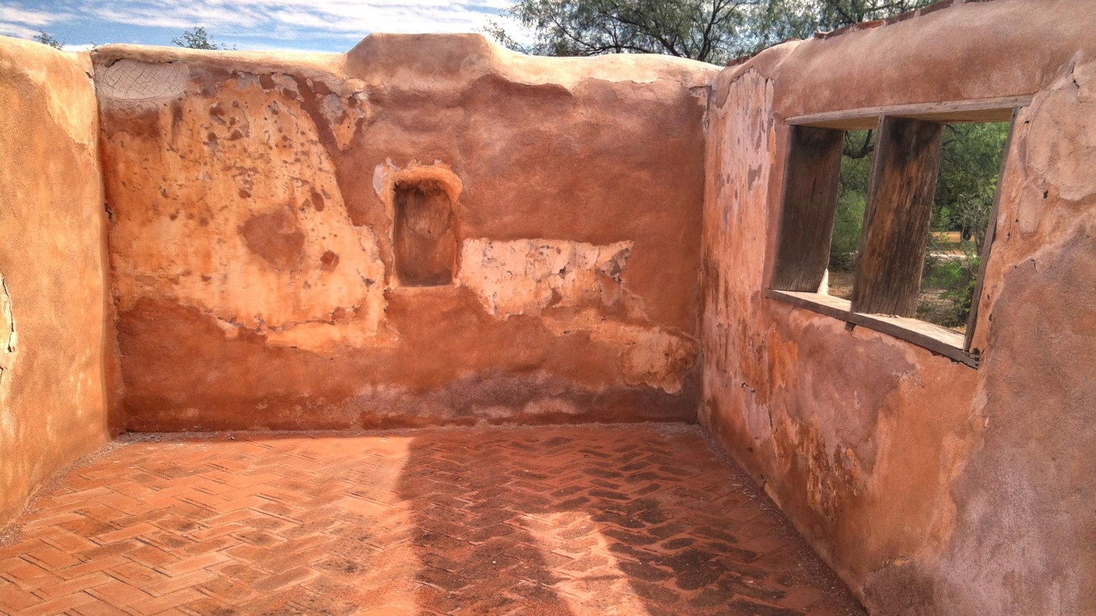 interior view of roofless structure with niche on far wall and herringbone tile pattern