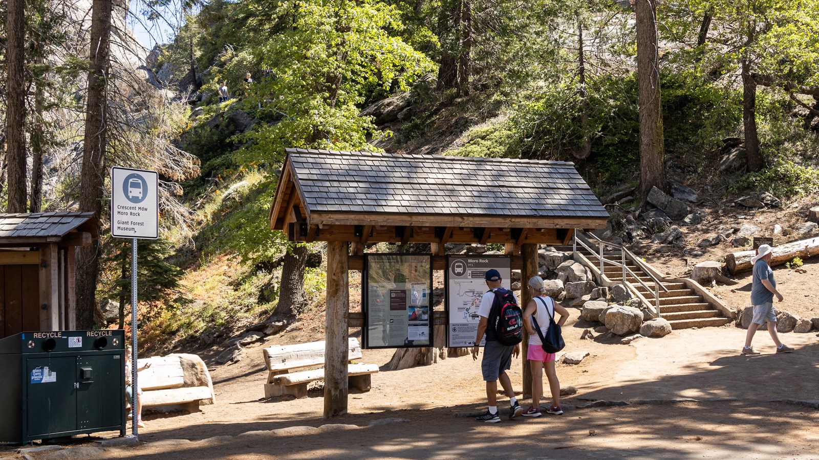 Park visitors read information at a wooden kiosk labeled