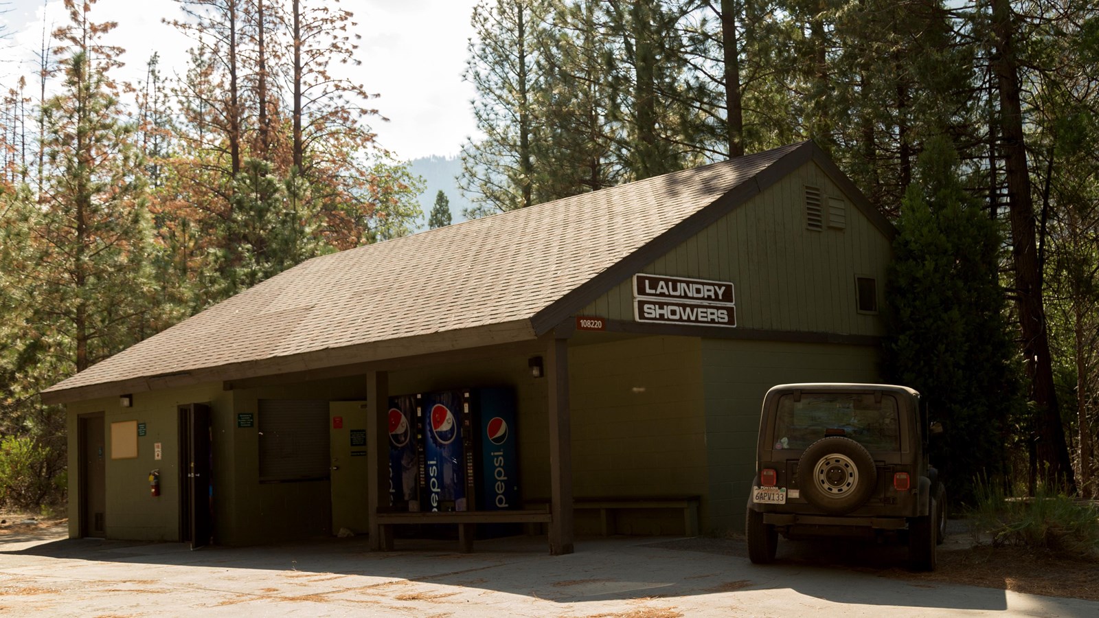 A small wooden green building houses the showers and laundry area of Cedar Grove. 