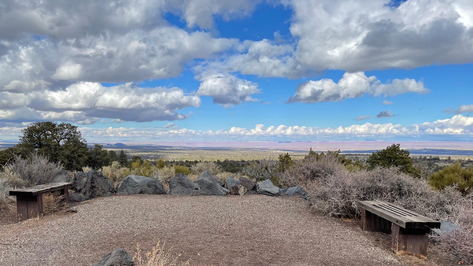 Two benches along a gravel path overlook a wide scenic view of the Painted Desert. 