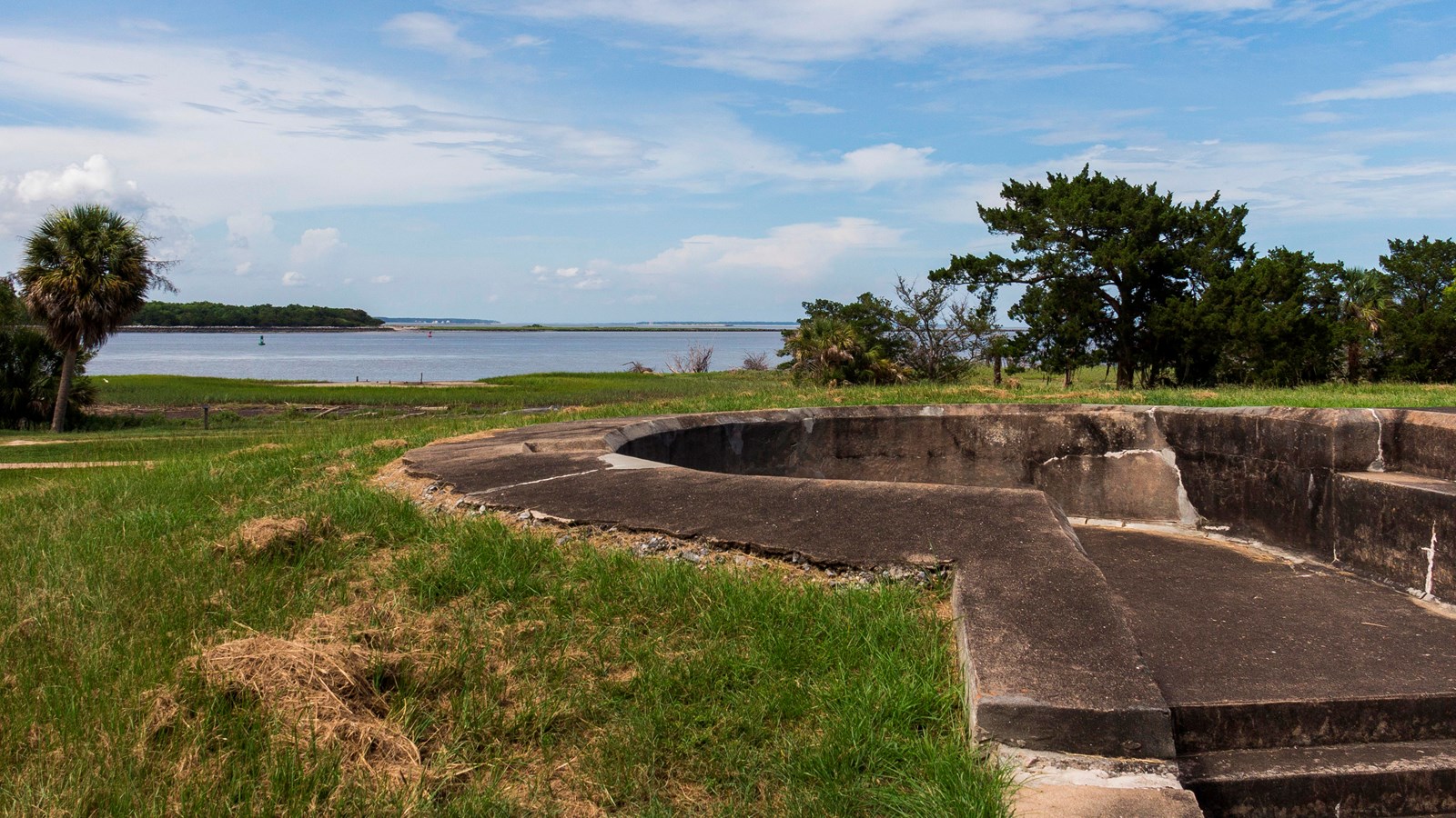 In a small hill overlooking the river water, a concrete gun battery, absent its guns, sits.