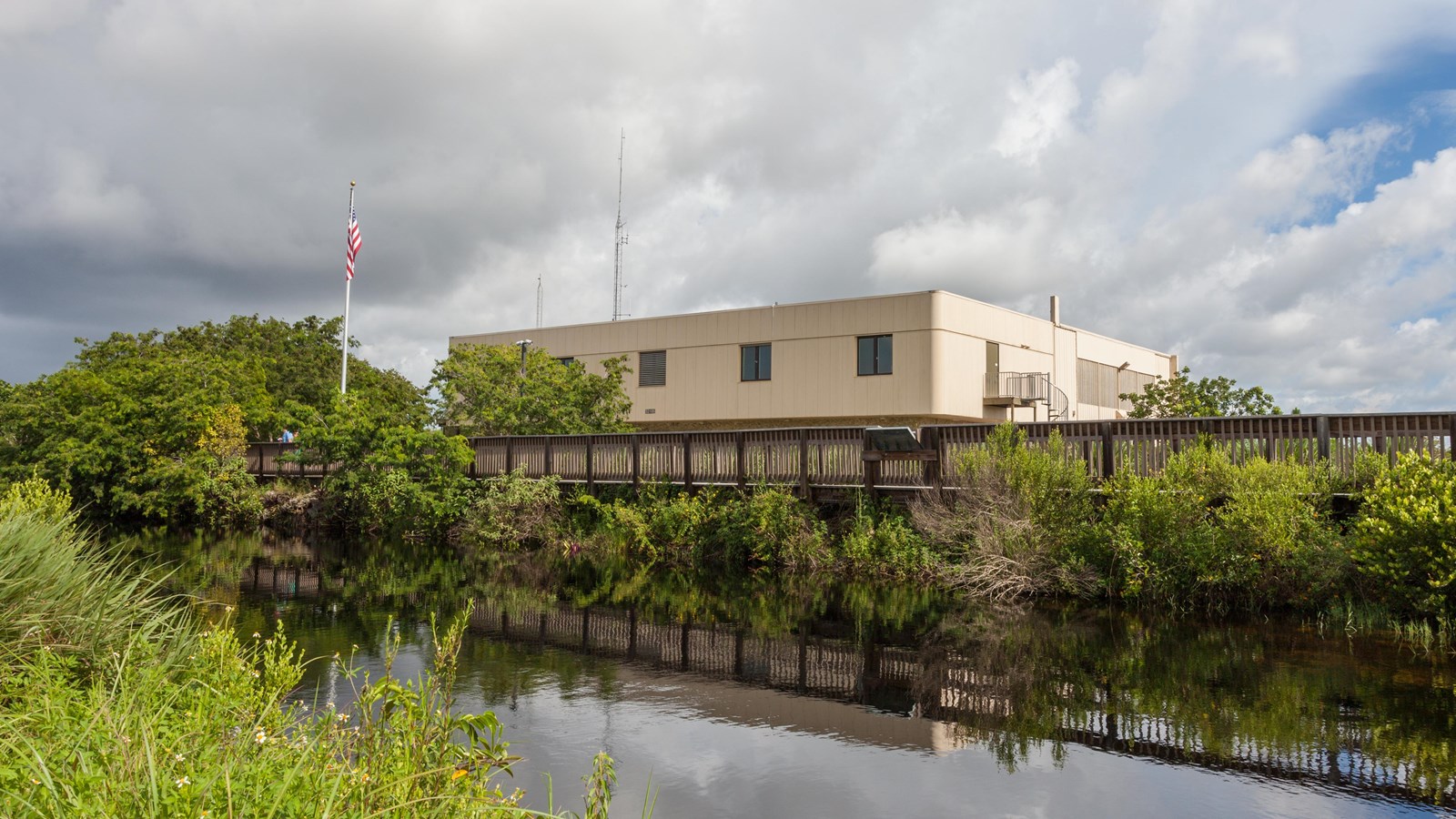 A large building with a boardwalk out in front overlooking a canal.