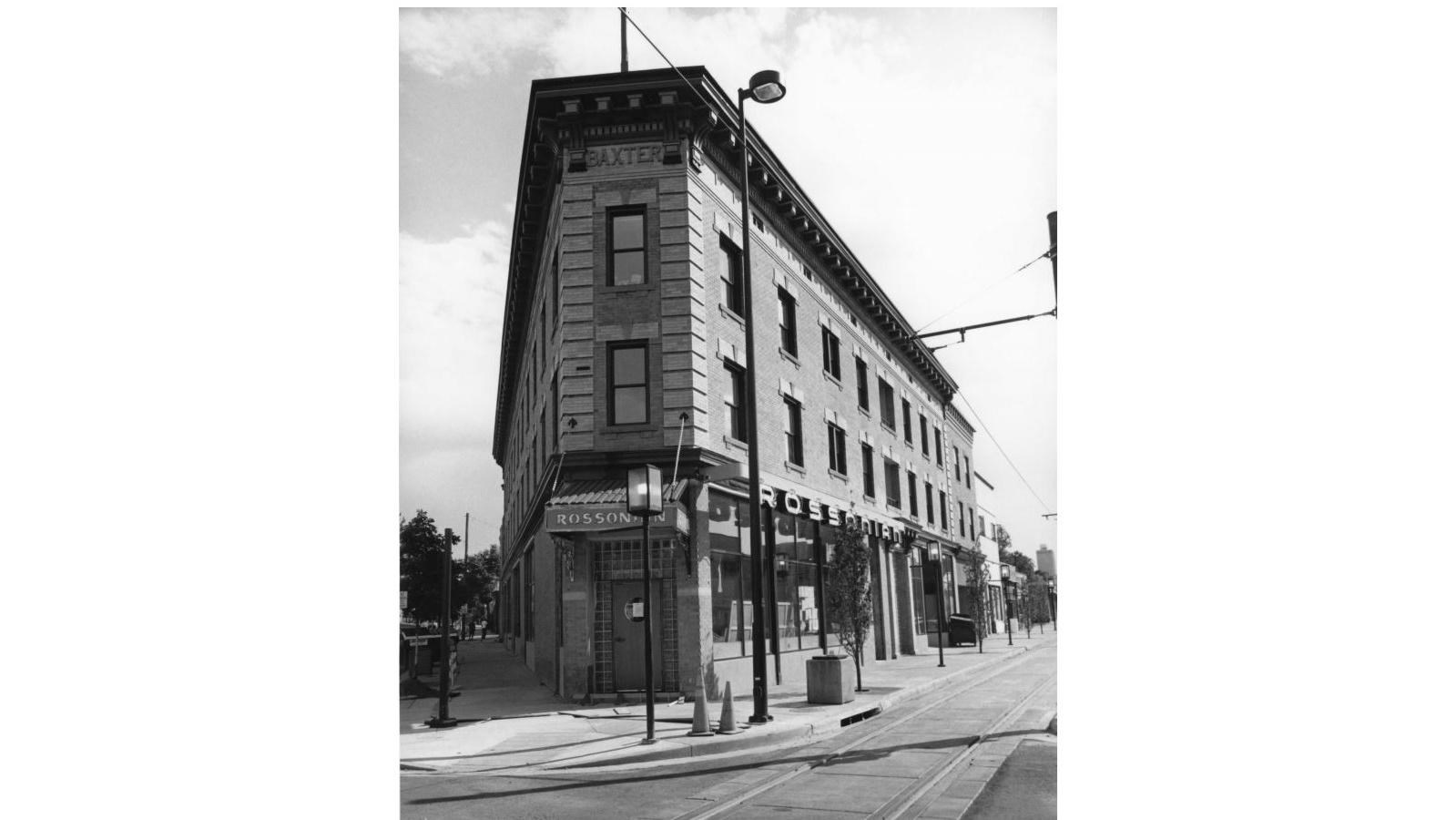 corner entrance façade of a three-story store front building on the corner of an intersection 