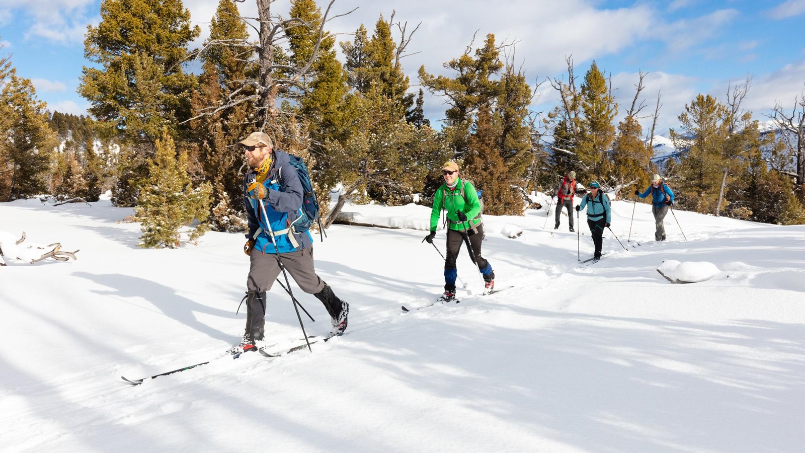 A person hikes through a green meadow surrounded by forest.