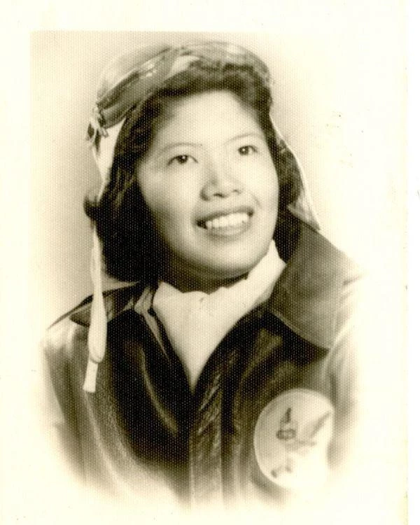 A portrait of Maggie Gee in her WASP uniform. She is wearing a bomber jacket with aviator goggles.
