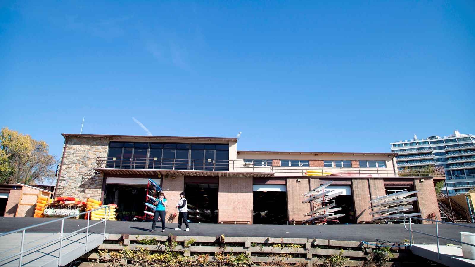 A two story structure with four garage doors on the ground level. Boats are stacked on dock