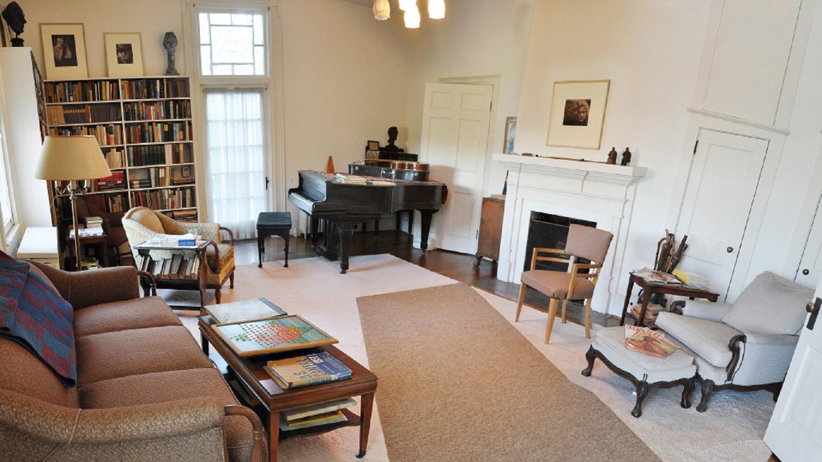 Vintage 1950\'s living room with sofa, chairs, piano, bookshelves and fireplace