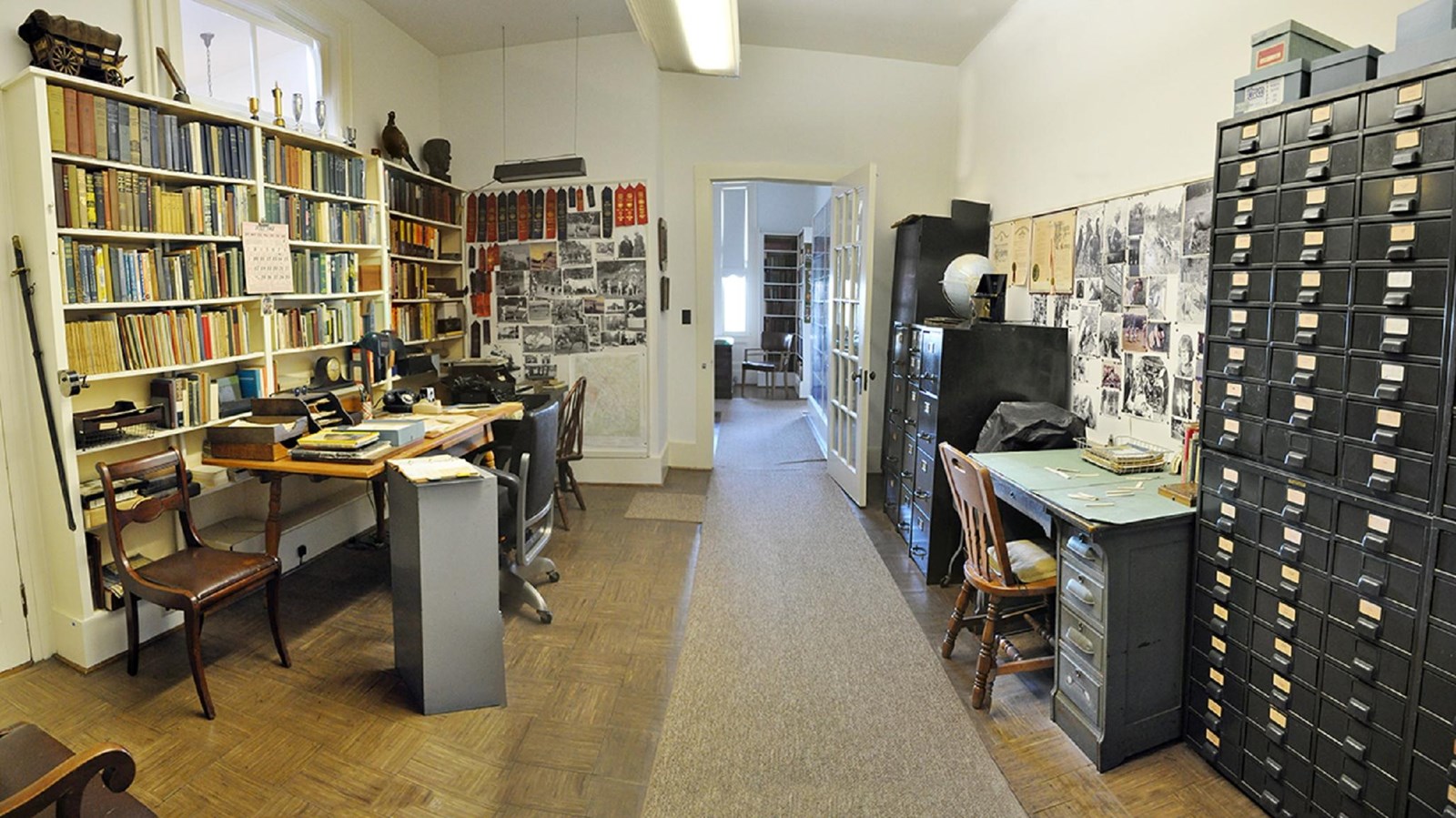 Room filled with books, filing cabinets, images of goats, award ribbons, and office supplies. 