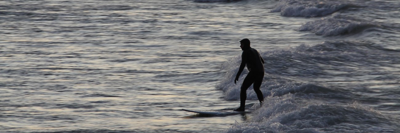 Surfer rides the waves at Portage Lakefront and Riverwalk at the Indiana Dunes National Park.