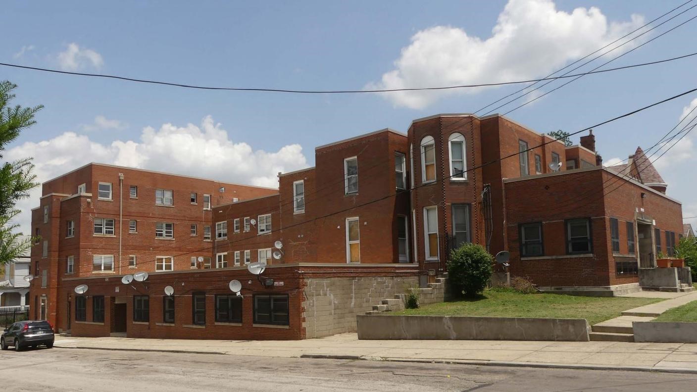 geometrically shaped brick building with satellite dishes attached to the street level entrance