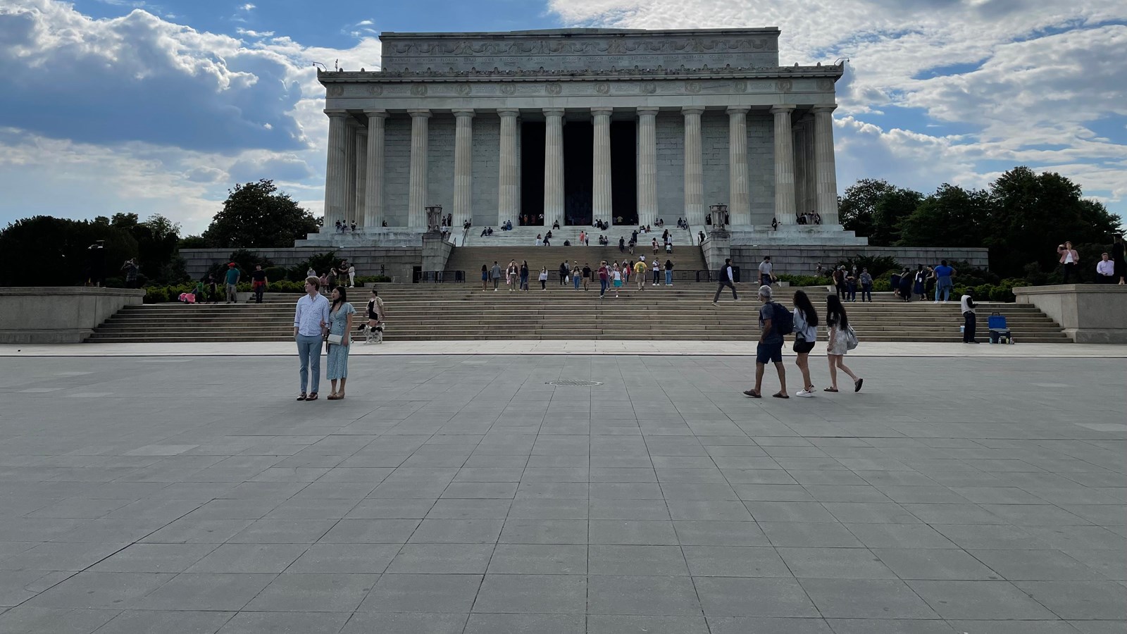 Paved walkway leading to steps which rise to the entrance of a white, columned building