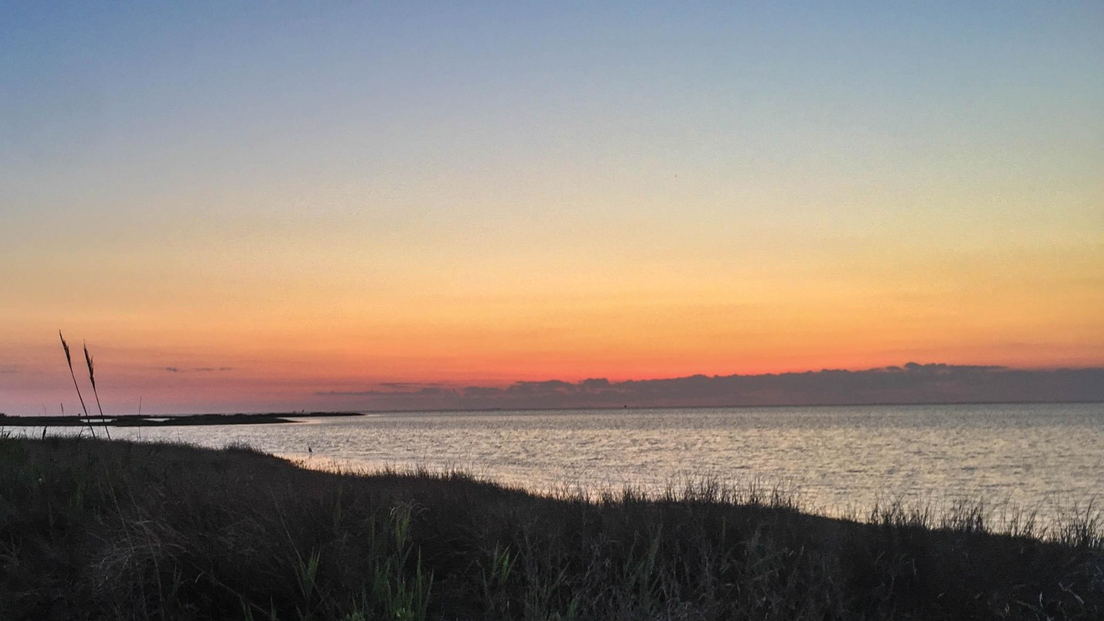 Sunrise over a dark ocean and light sandy beach