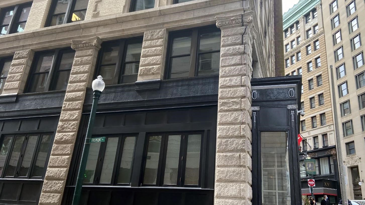 A multi-story building. First floor exterior is black molding around windows between stone columns.