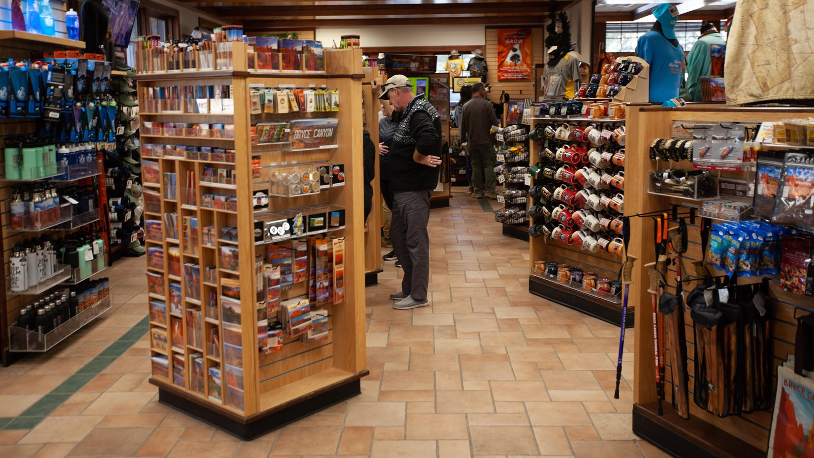 Two adults browse souvenirs in a gift shop full of mementos and supplies